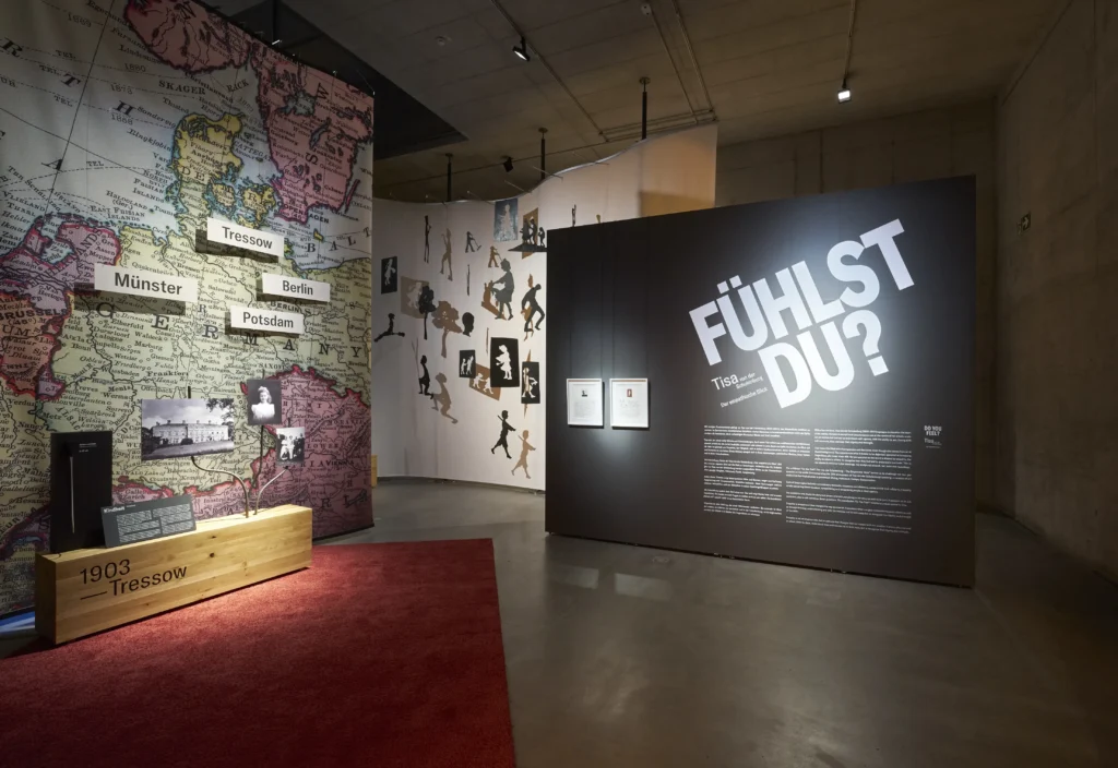 Ausstellungsbereich mit einer großen historischen Landkarte, Stationen zu Tressow, Münster, Berlin und Potsdam sowie einer Einführungstafel mit der Überschrift „FÜHLST DU?“. Im Vordergrund stehen Vitrinen und historische Fotografien.